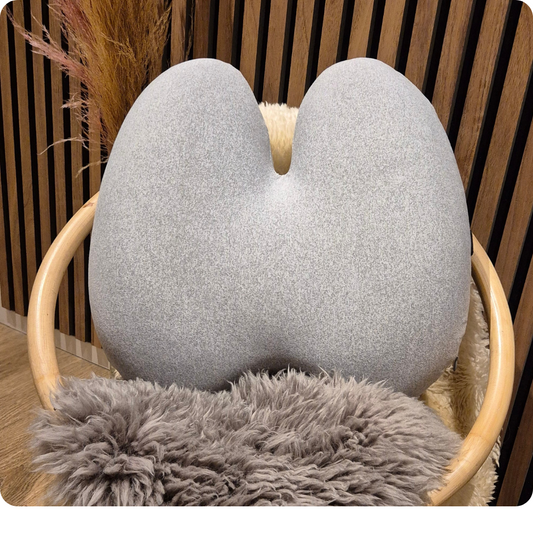 Ergonomisk memory foam rygpude i grå fra Copenhagen Comfort, placeret på stol med blødt pelsunderlag. Aflaster ryg og giver støtte i hjemmet