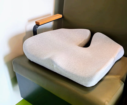 Grå ergonomisk memory foam siddepude på togsæde, ideel til rejser og længere siddeture. Copenhagen Comforts pude giver støtte og komfort på farten.